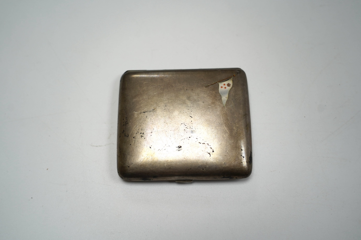 An early 20th century continental 800 standard white metal cigarette case with enamelled ensign, 89mm, gross weight 4oz. Condition - poor